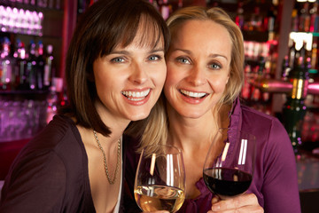 Two Women Enjoying Drink Together In Bar
