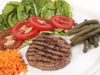 Hamburguesa en plato blanco con verduras vista de arriba