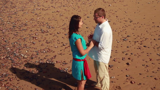 Man proposing marriage to surprised woman on the beach