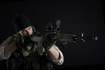 Soldier with rifle against black background.