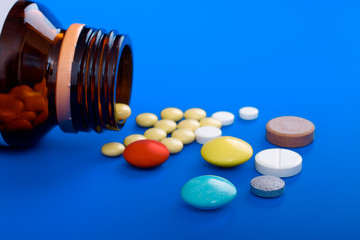 Spilled tablets and medicine bottle. Tablets on a blue backgroun