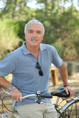 Fototapeta premium Relaxed senior man leaning on his bike