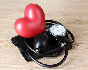 Black tonometer and heart on wooden background
