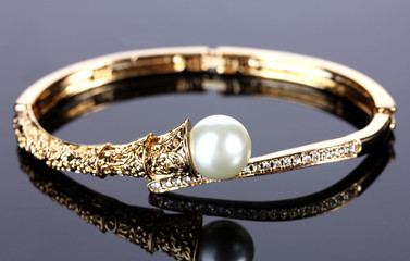 Beautiful golden bracelet with pearl on grey background