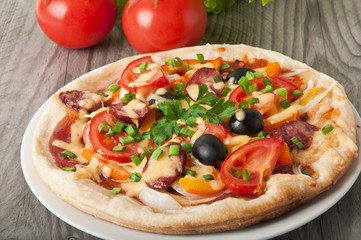 Closeup of pizza with tomatoes, cheese, black olives and peppers