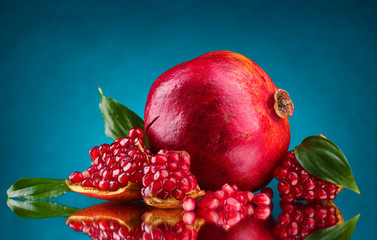 ripe pomegranate fruit with leaves on blue background