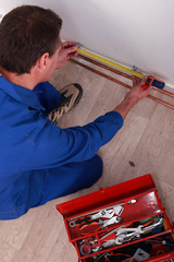 Plumber measuring length of copper pipe