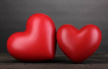 Fototapeta premium Two decorative red hearts on wooden table on grey background
