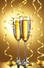 glasses of champagne and streamer on yellow background