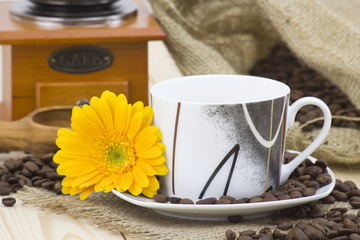 cup of coffee with orange gerbera and coffee beans