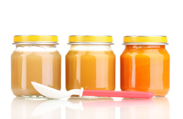 Jars of baby puree and spoon isolated on white
