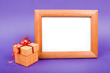 Wooden photo frame and orange gift box with red ribbon on blue b