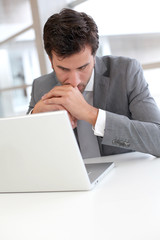 Portrait of worried businessman in front of laptop