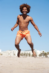 Fototapeta na wymiar young african american male jumping at beach