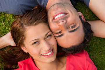 Fototapeta premium Close-up of two friends looking upwards while lying head to shou