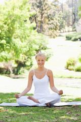 Smiling woman sitting in a yoga position in the park