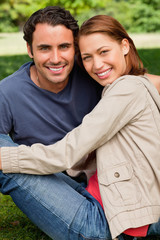 Obraz premium Two friends smiling and looking in front of them as they sit nex