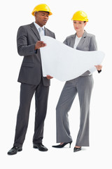 Businessman and woman with hard hats holding paper