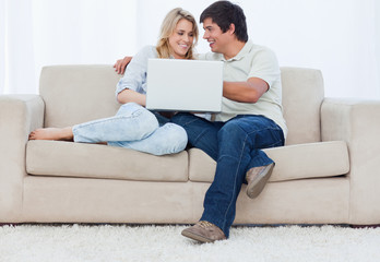 A young couple sitting on a couch with a laptop