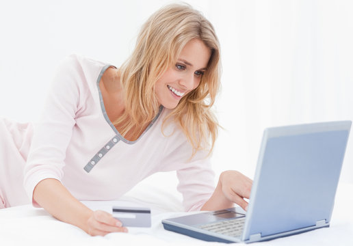 Woman smiling using her credit card and laptop to order online