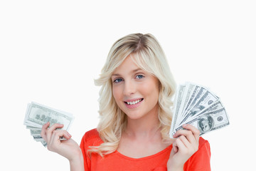 Woman showing a great smile while holding two fans of dollar not