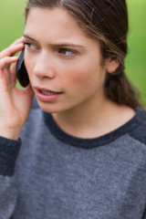 Young serious girl talking on the phone while looking towards th