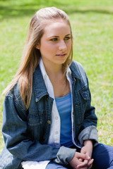 Young blonde girl looking towards the side while sitting down in