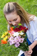 Fototapeta premium Young attractive girl smelling a bunch of flower