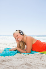 Young blonde woman lying down while listening to music