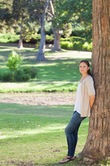 Naklejka premium Woman in the countryside leaning against a tree