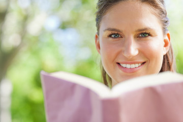 Fototapeta premium Smiling woman reading a book in the park