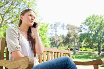 Woman talking on her phone on a park bench