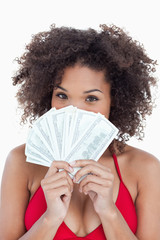 Brunette woman hiding her face behind a fan of notes