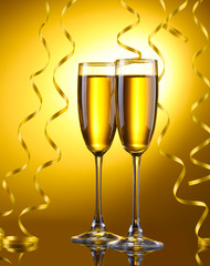 glasses of champagne and streamer on yellow background