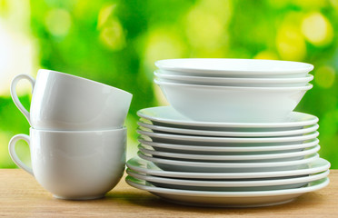 Clean dishes on wooden table on green background