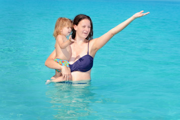 Obraz na płótnie Canvas Happy child with her mother on the beach