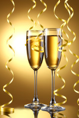 glasses of champagne and streamer on yellow background