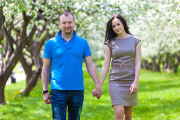 Obraz premium Young Couple in love in the spring blossoming apple orchard