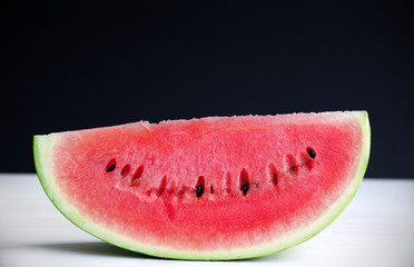 Watermelon, ripe and juicy slice on a black background