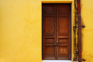 Fototapeta premium wooden door on yellow wall in old palace, Thailand