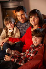 Portrait Of Family Relaxing On Sofa By Cosy Log Fire