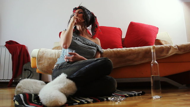 Young woman drinking and smoking at home