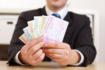 Manager im Büro hält Geldscheine
