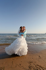 Fototapeta na wymiar Bride and groom kissing at the beach
