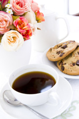 Chocolate chip cookie  on white plate with black coffee and flow