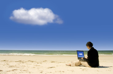 Businesswoman working with laptop at beach