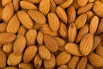 Heap of raw almonds nuts background