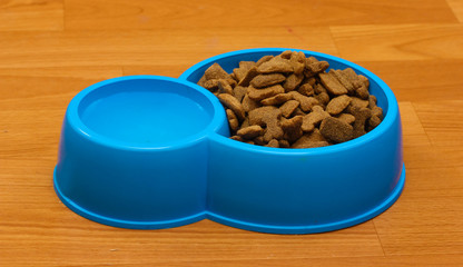 dry dog food and water in blue bowl on the floor