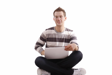 Young man sitting with laptop cross-legged on floor