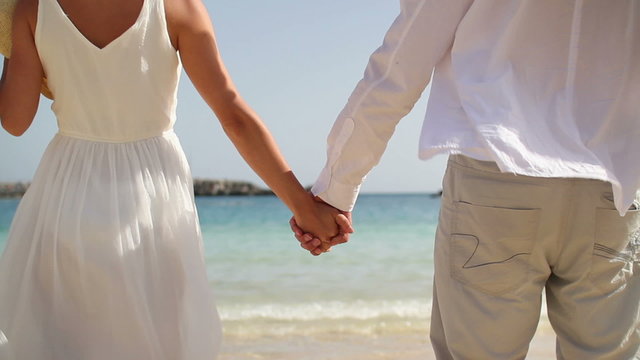 Closeup shot of a couple holding hands on the beach